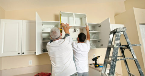 couple setting up cabinetry with power tools
