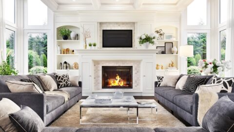 interior of well decorated home with burning fire place in center and lots of plush seating