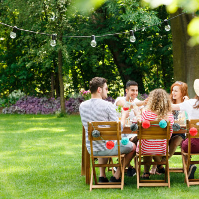 people cheersing at a table in the backyard with festive decor and lights